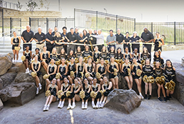  A large group of people cut a large gold ribbon